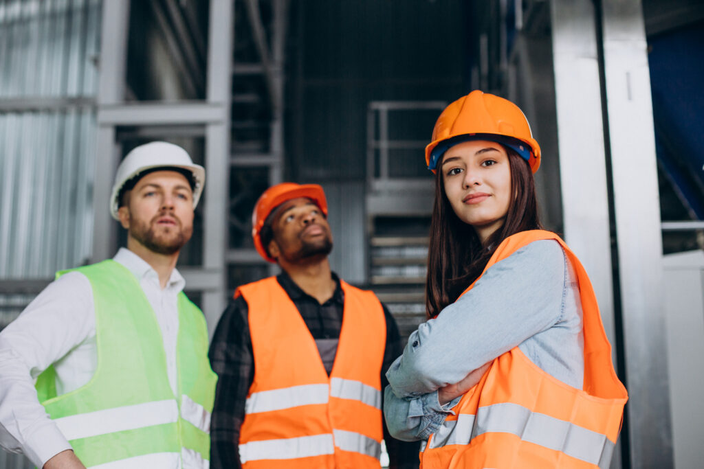 three factory workers safety hats discussing manufacture plan 1 Atcon System